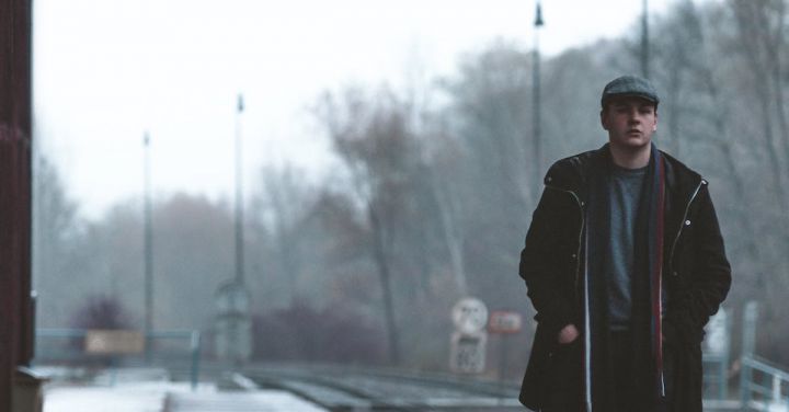 Winter Railway - Unemotional man standing on railroad station platform on winter day