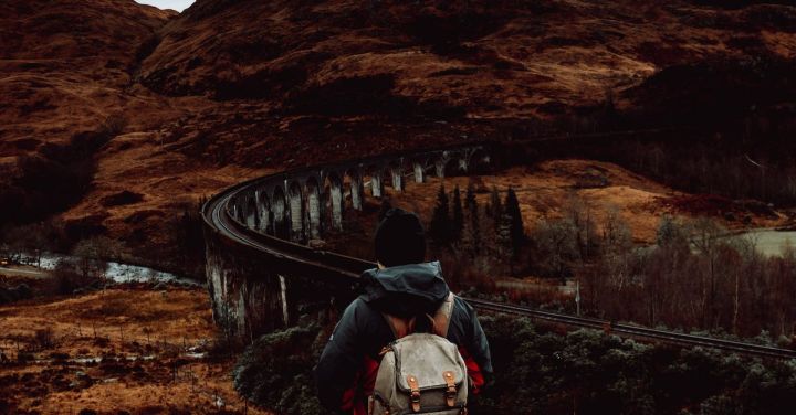 Hogwarts Express - Man Standing on Hill Looking at the Glenfinnan Viaduct in Scotland