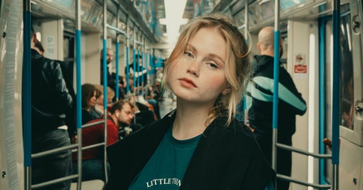 Train Travel - Young Woman in a Teal T-Shirt Standing on a Metro Train