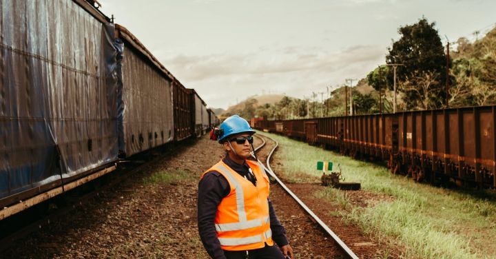 Railroad Worker - A Worker Wearing a Safety Helmet and Safety Vest while Standing on a Railway